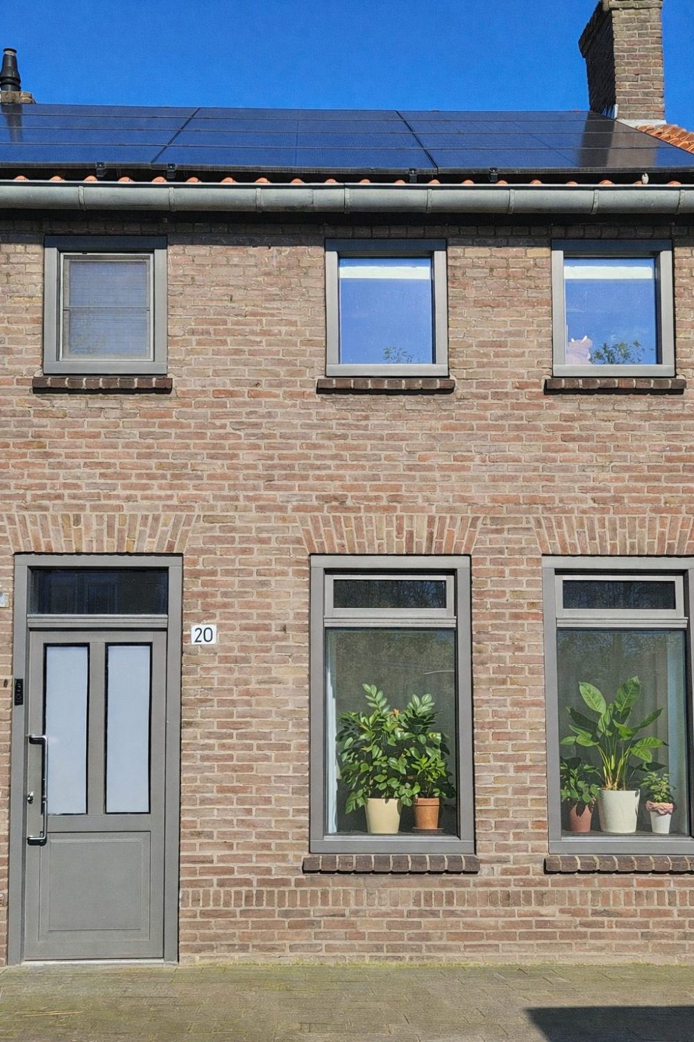 Kunststof blokkozijnen in kwartsgrijs met houtnerf en aluminium schuifpui in aanbouw